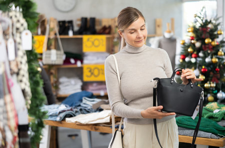 adult woman chooses fashionable handbags in a store against the background of a Christmas treeの写真素材