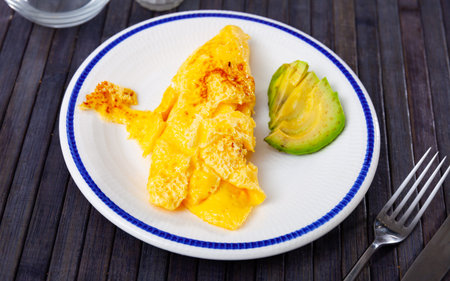 Idea for healthy and low-carb breakfast is omelette and half chopped avocado.の写真素材