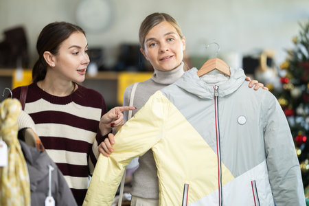 Two women choosing a coat or jacket together in a clothing store for Christmasの写真素材