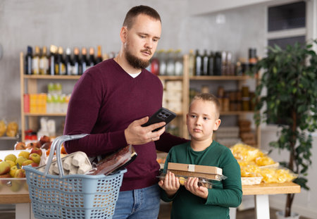 Man with phone and son choosing groceriesの写真素材