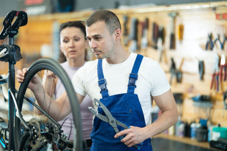 Young male worker repairing clients bike
