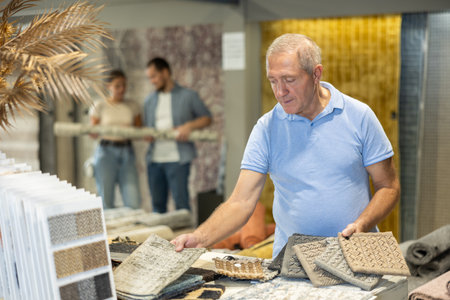 Elderly man choosing carpet samples in storeの写真素材
