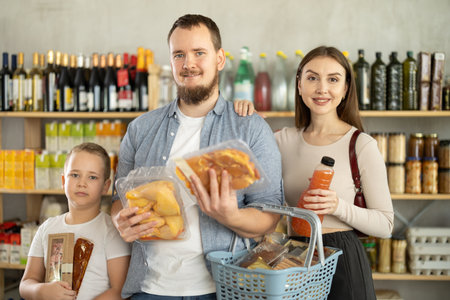 Couple of man and woman with boy choosing food in groceryの写真素材
