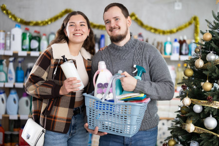 Happy couple shopping for cleaning products and toiletries in festive storeの写真素材