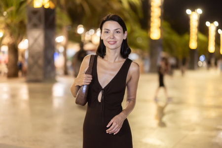 Woman walking along coastal promenade at night in Barcelonaの写真素材