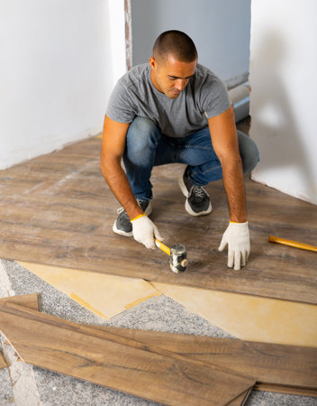 Man using hammer to lay down wooden parquet on floorの写真素材