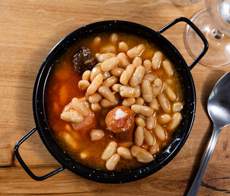 There is traditional Spanish dish on table - Fabada Asturian in potの写真素材