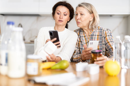 Adult daughter and elderly mother scan barcode on food package together using smartphone
