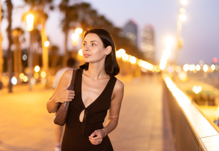 Young woman standing at parapet at Barceloneta beach in summer eveningの写真素材