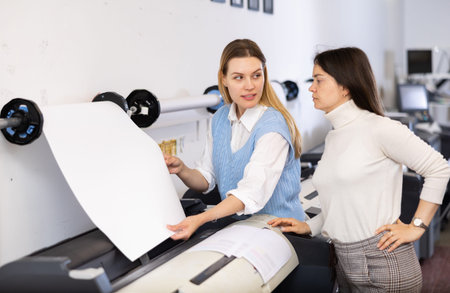 Printing office manager and employee loading printer with paper