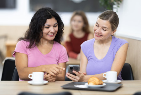 Young and adult women with phone in cafe