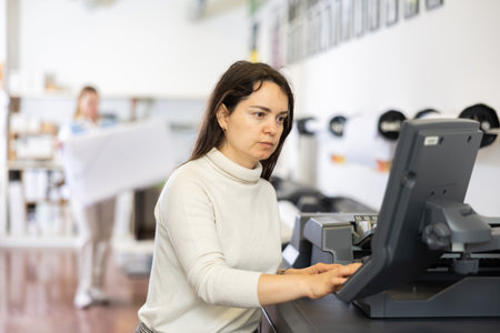 Female employee of the printing house adjusts the plotter using computerの写真素材
