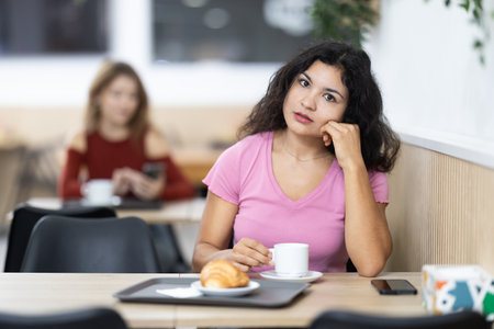 Young woman drinking coffee with croissant in cafeの写真素材