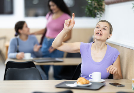 Adult woman calls waiter in cafeの写真素材