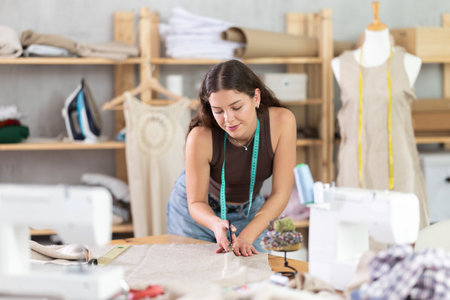 Woman tailor cutting fabric on tableの写真素材