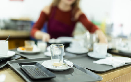 Young female waitress collects dirty dishesの写真素材