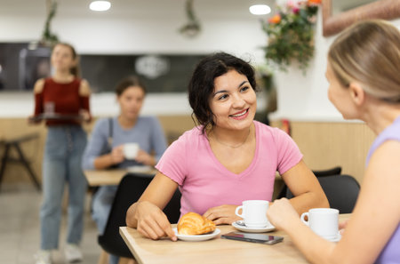 Young woman and her friend drinking coffee and talkingの写真素材