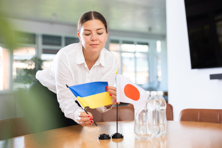Positive young woman putting little flag of Ukraine on table next to the flag of Japanの写真素材