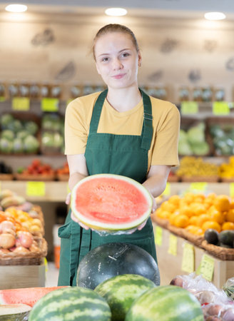 Grocery store saleswoman offers to buy ripe watermelonの写真素材