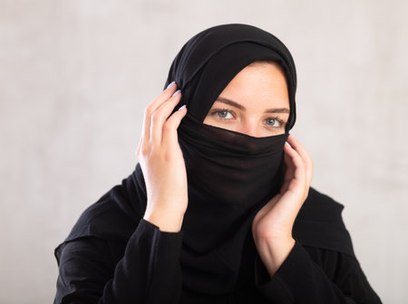 Muslim woman with face covered holds thin fabric with her handsの写真素材