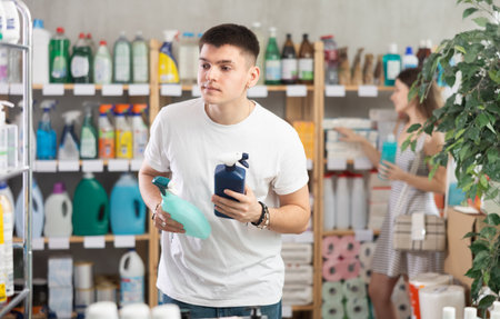 Man view on label, pick eco friendly glass cleaner, woman shopping in backgroundの写真素材