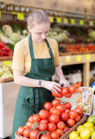 Female seller laying out tomatoes on the counterの写真素材