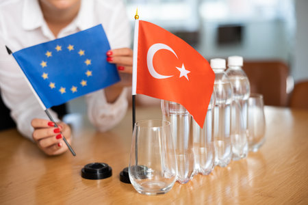 Little flag of Turkey on table and flag of European Union put next to it by young womanの写真素材
