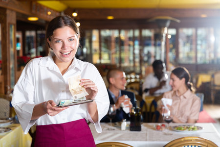 Happy woman waiter with good tip in restaurantの写真素材