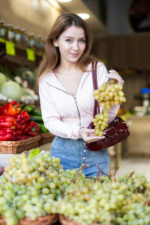 Young woman choosing ripe grapesの写真素材