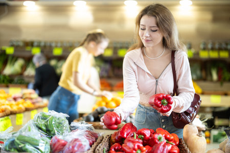 Young woman choosing peppers in the storeの写真素材
