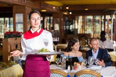 Waiter standing with serving tray, recommending dishes in restaurantの写真素材