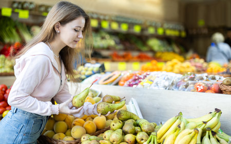 Young woman chooses pears in storeの写真素材