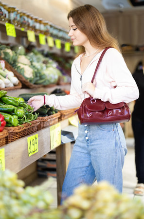 Young woman chooses peppers in storeの写真素材