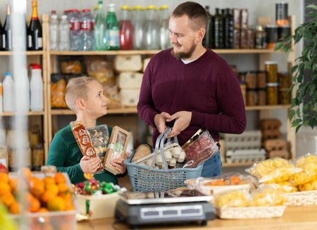 Young man with son choosing sweets at grocery storeの写真素材
