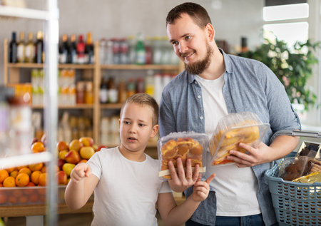 Father and preteen son choosing packaged cut meat in grocery storeの写真素材
