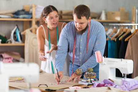 Male and female dressmakers drawing with curvesの写真素材