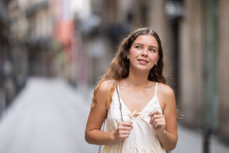 Young woman in white dress walking along the streets of the historical center of cityの写真素材