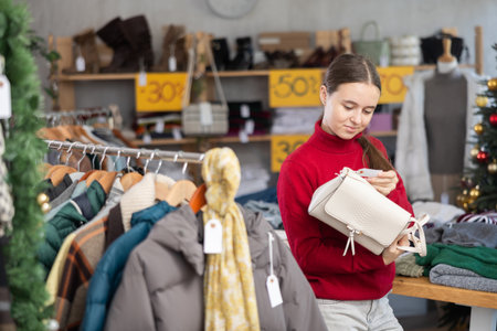 Teenage girl chooses a fashionable handbag in clothing storeの写真素材