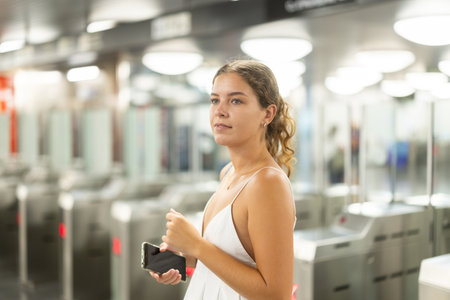 Thoughtful young girl passing through terminal in subway stationの写真素材