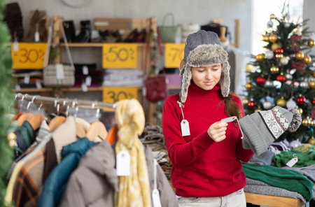 Teenage girl chooses a warm hat in fashion boutique.