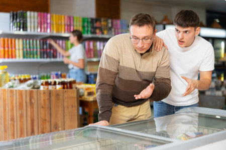 Father and son choosing frozen products in refrigerated display in supermarketの写真素材