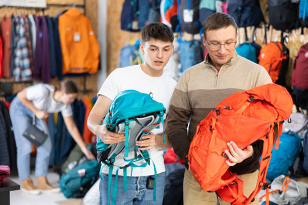 Father and son choose a backpack for hike together in store that sells sports equipmentの写真素材