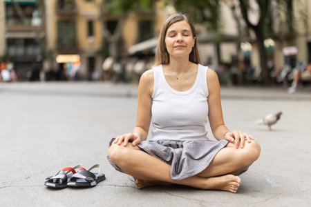 Woman in midst of bustle of city in pose of lotus asanaの写真素材
