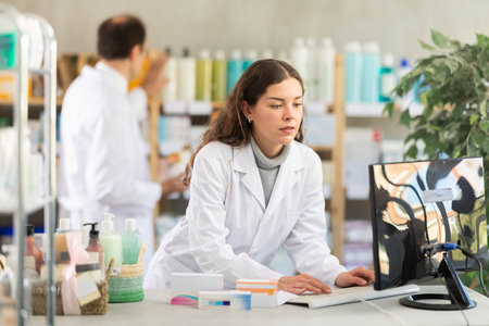 Female pharmacist looking for pills on computerの写真素材