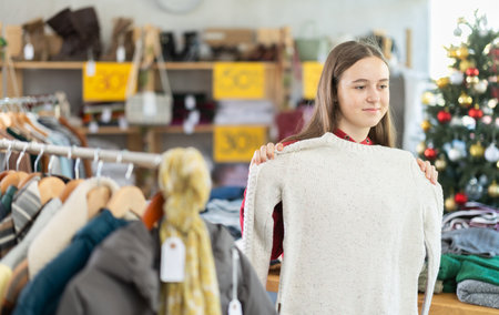 Teenage girl chooses sweater in clothing storeの写真素材