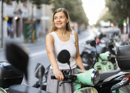 Woman rents moped, starts journey at parking lotの写真素材