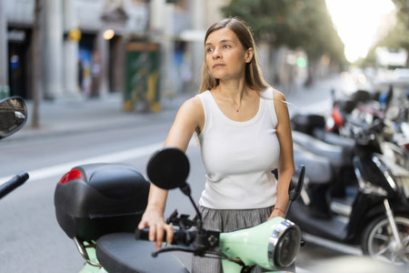 Woman rents moped, starts journey at parking lotの写真素材