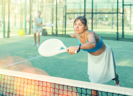 Young woman hitting ball with backhand during paddleball match outdoorの写真素材