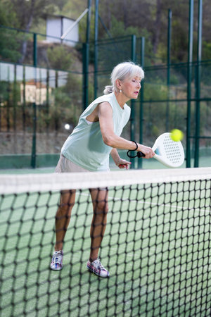 Elderly woman padel tennis player training on courtの写真素材