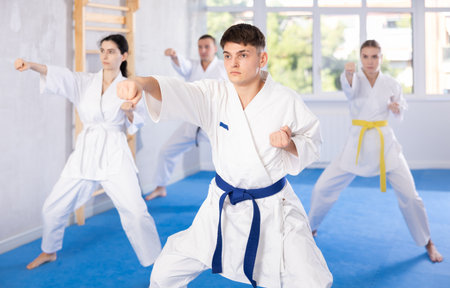 Middle-aged man attendee of karate classes practicing kata standing in row with othersの写真素材